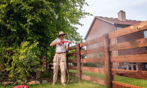 man-cleaning-a-wooden-fence-with-an-electric-power-washer